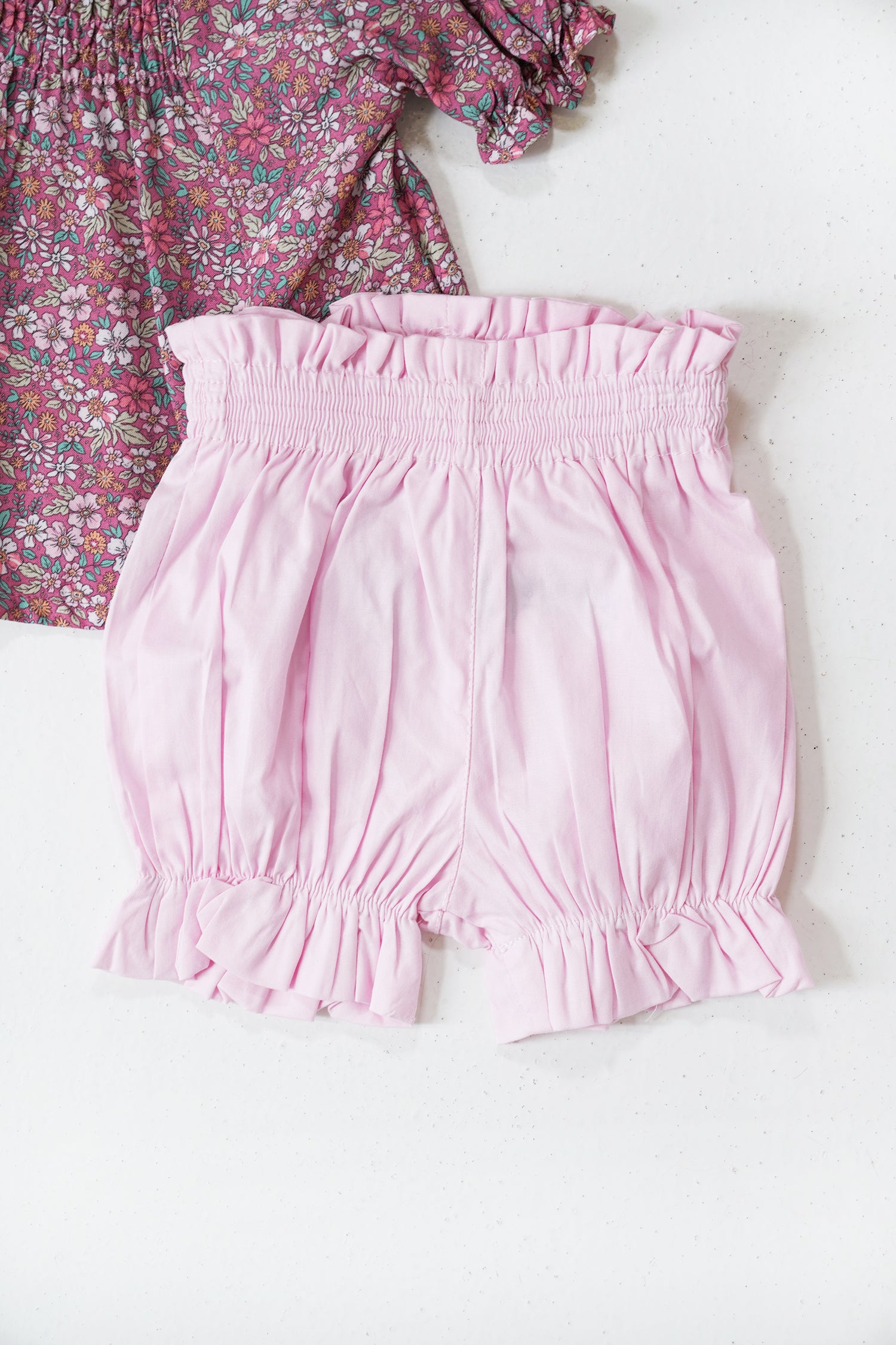 Pink shorts with a floral top on a white background