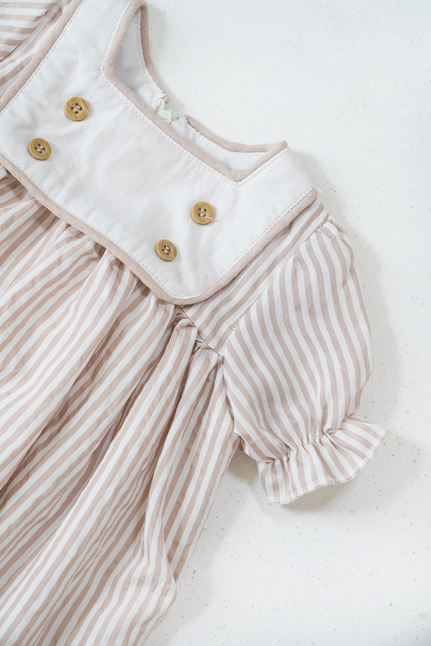 Striped baby romper with buttons on a white background