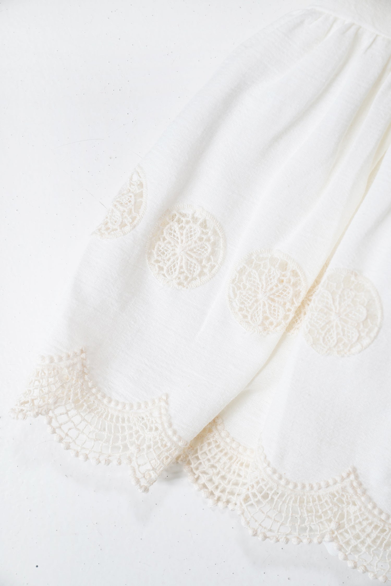Close-up of a white fabric with lace detailing on a white background