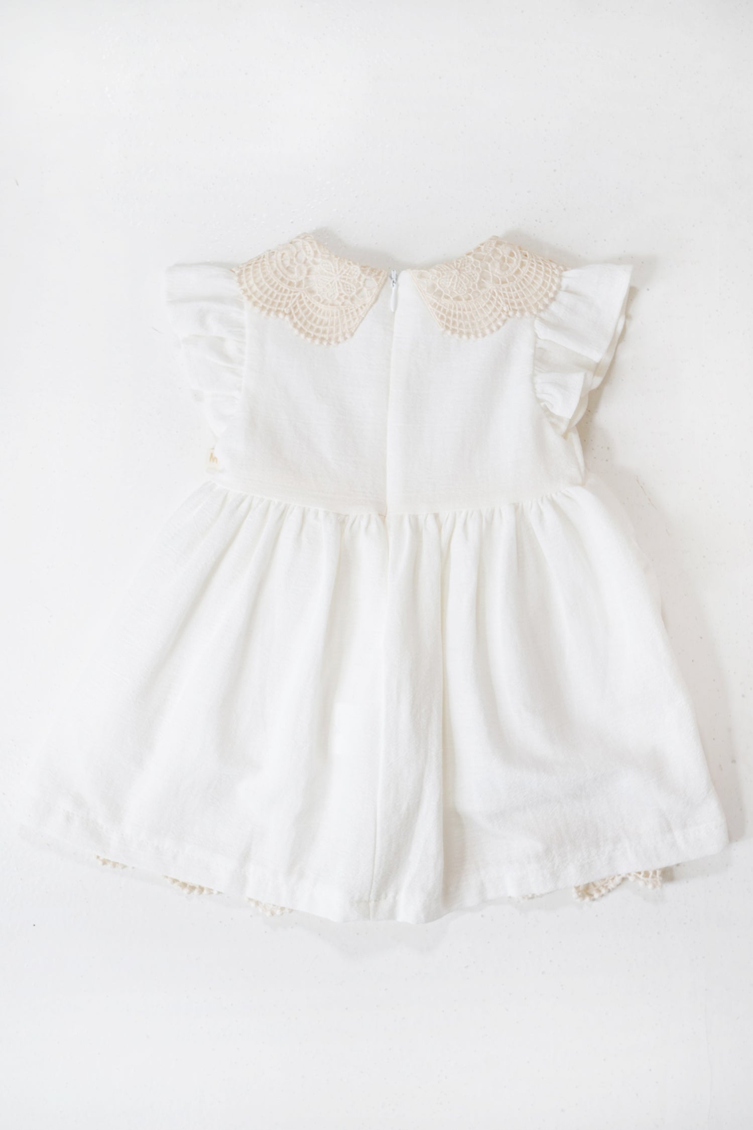 White baby dress with lace details on a white background