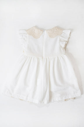 White baby dress with lace details on a white background
