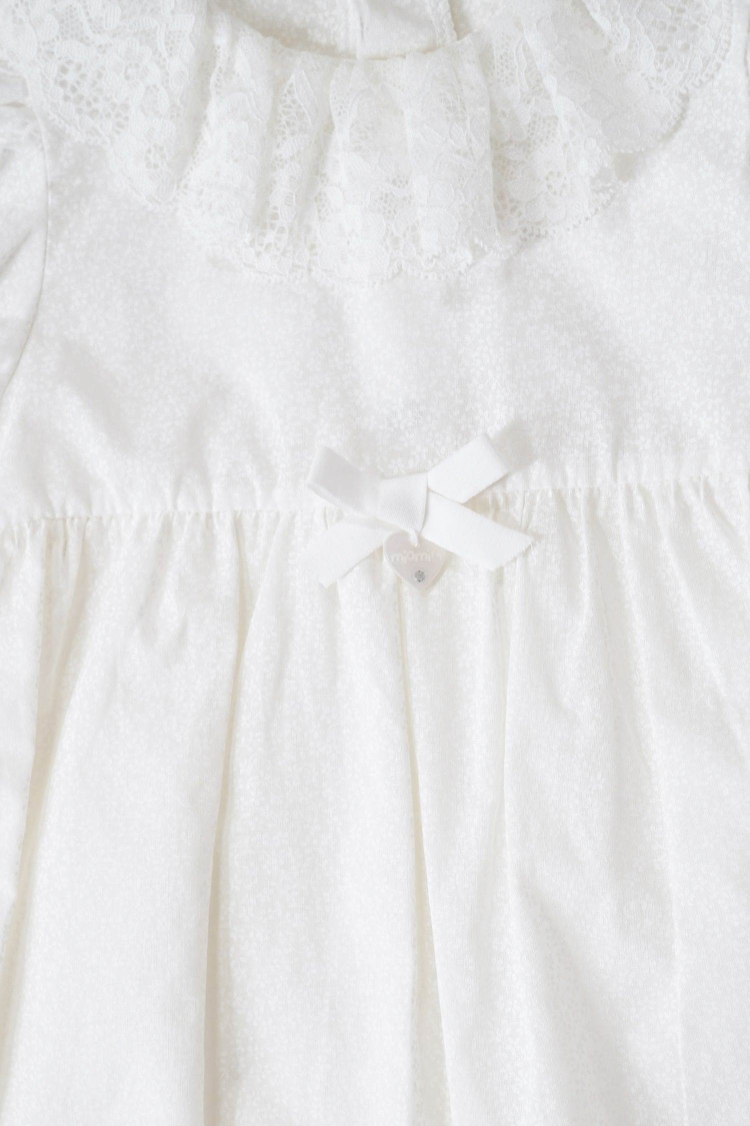 Close-up of a white dress with a bow detail on a white background