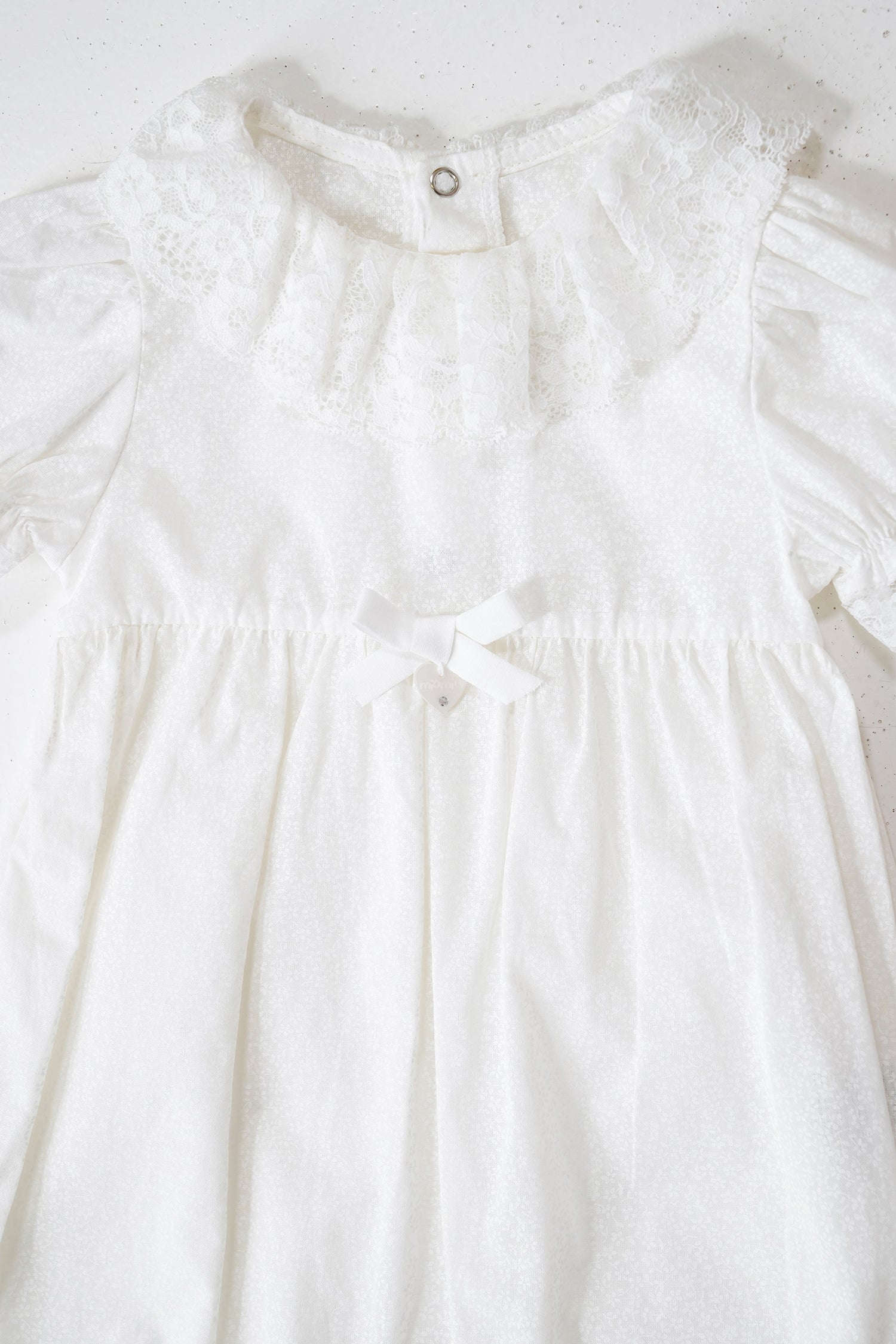 Close-up of a white dress with lace details on a light background