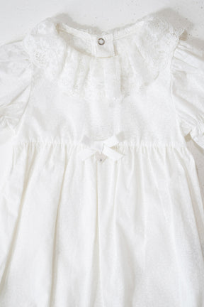 Close-up of a white dress with lace details on a light background