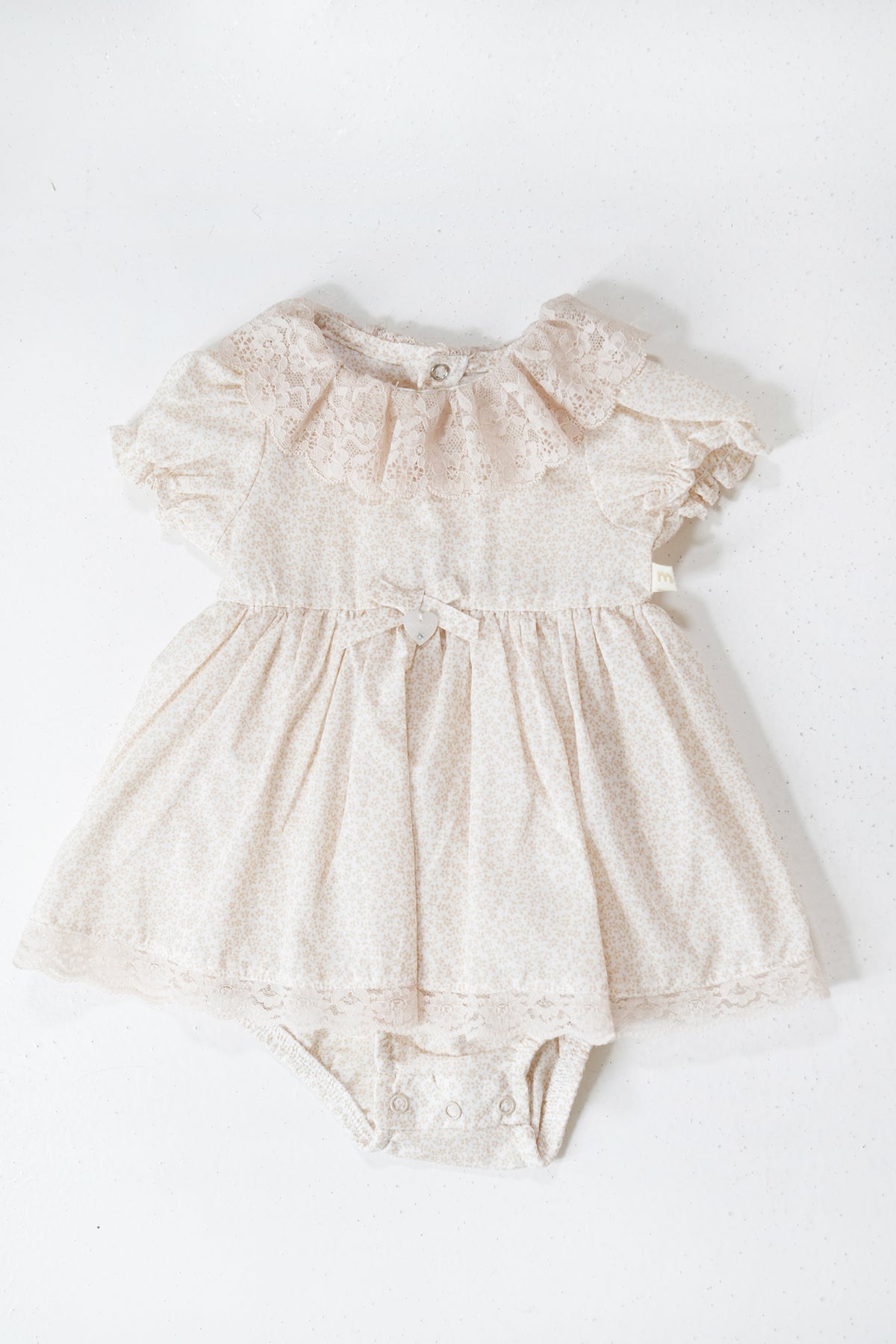 Beige lace baby romper on a white background