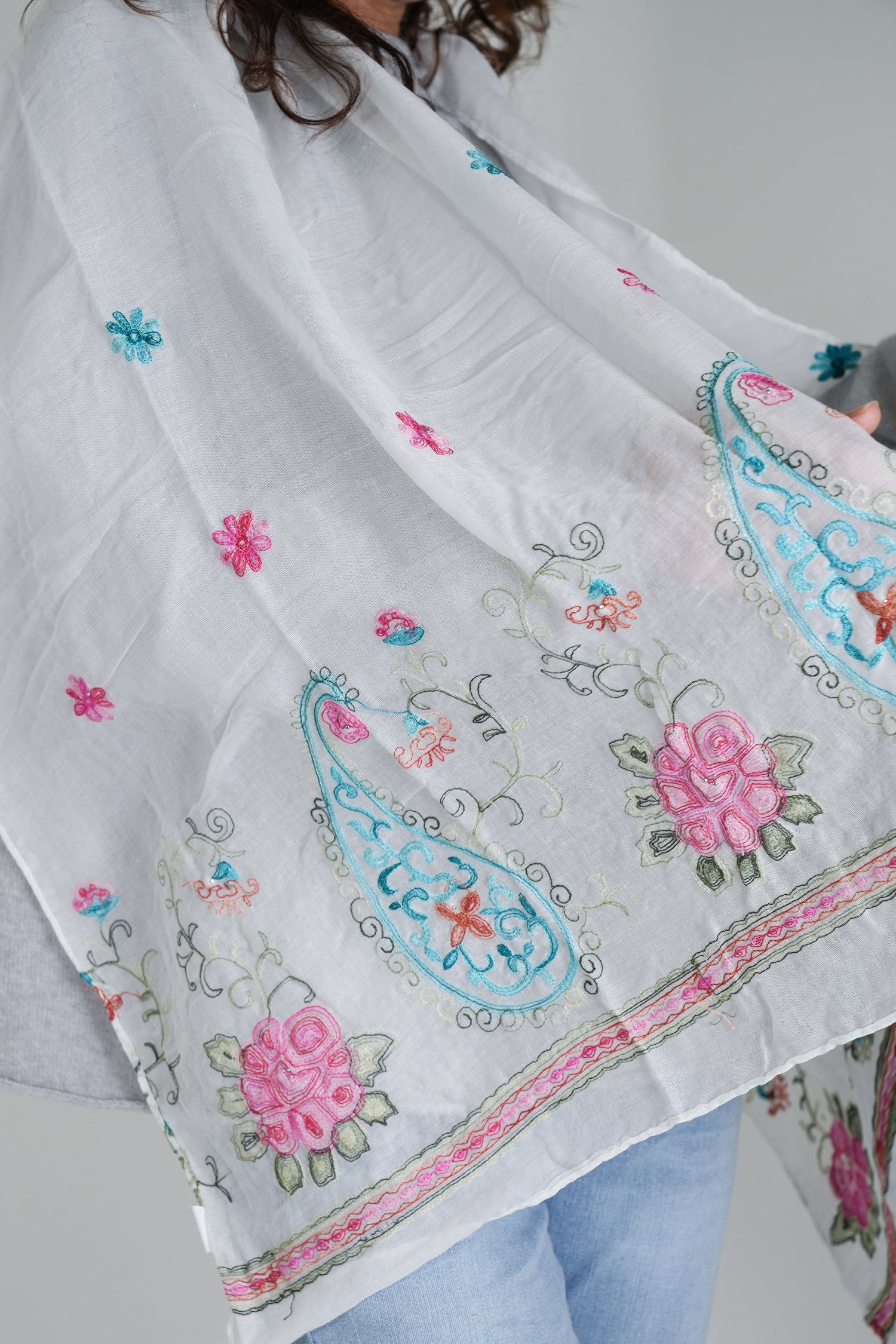 White scarf with colorful embroidery and floral patterns on a plain background