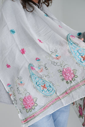 White scarf with colorful embroidery and floral patterns on a plain background