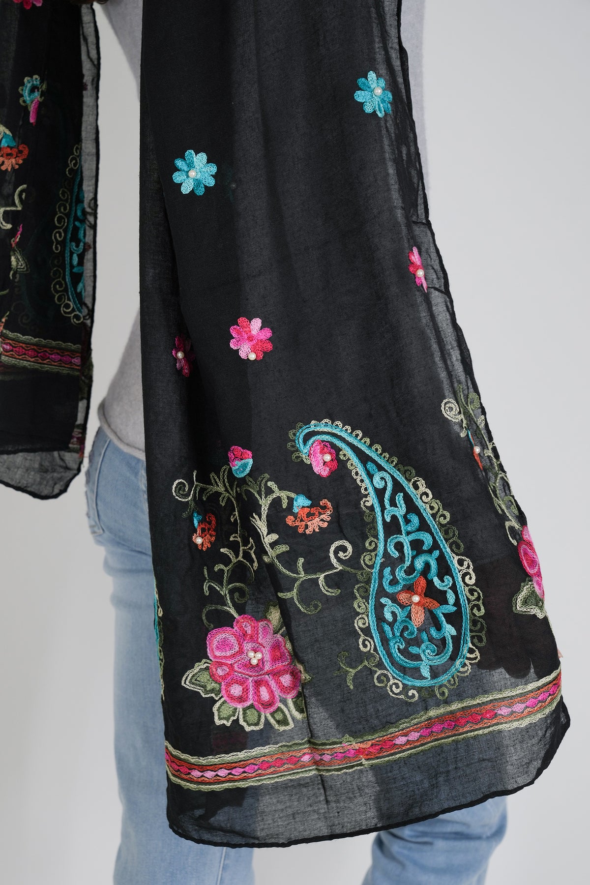 Black scarf with colorful floral and paisley embroidery on a plain background