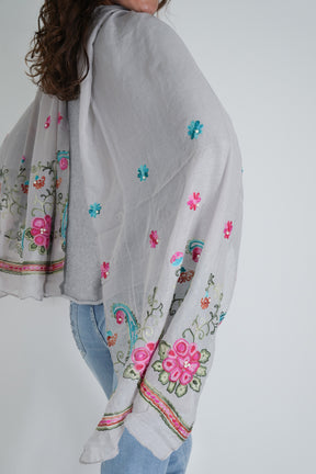 Gray blouse with colorful floral embroidery on a plain background