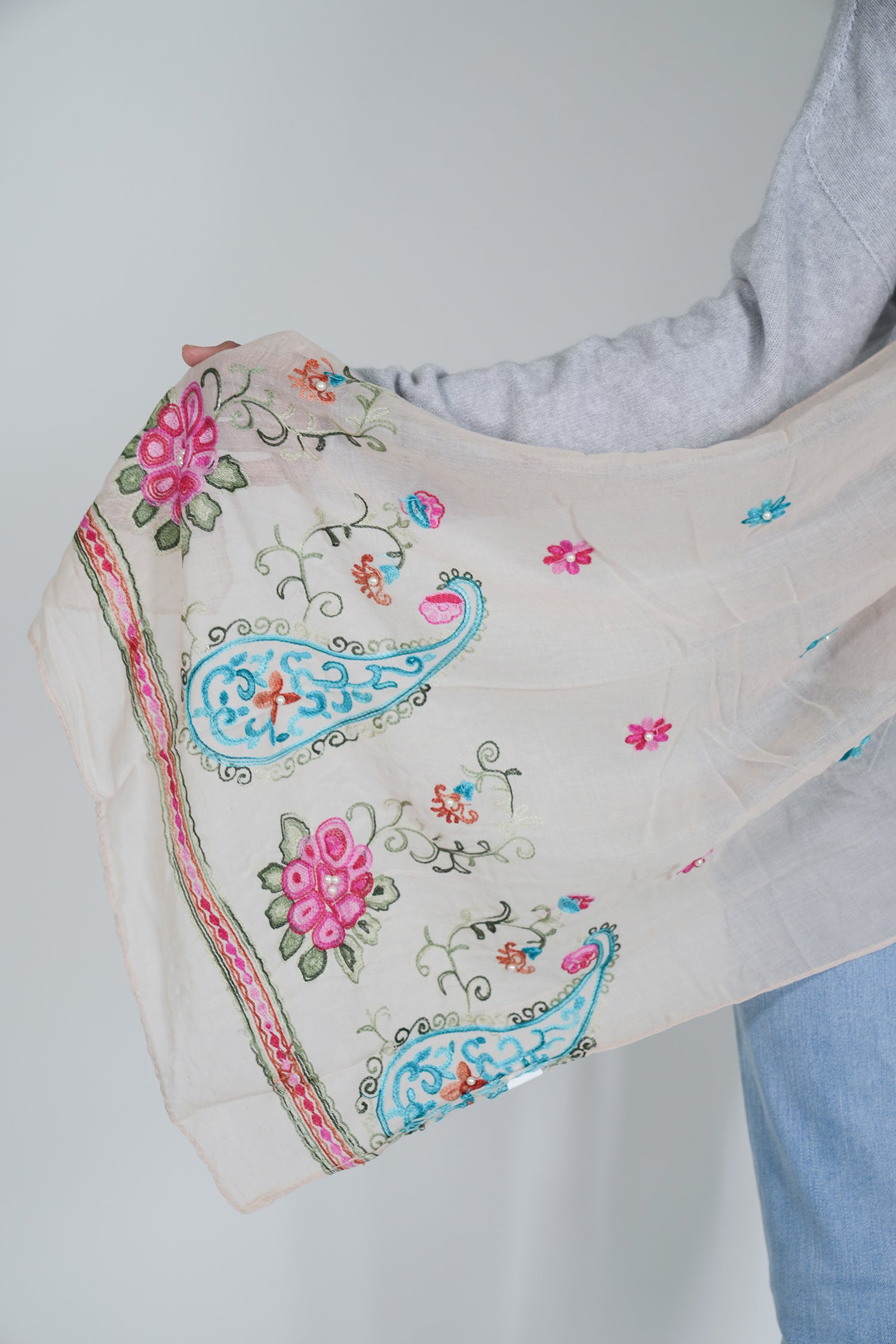 Embroidered fabric with floral and paisley patterns on a plain background