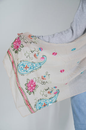 Embroidered fabric with floral and paisley patterns on a plain background