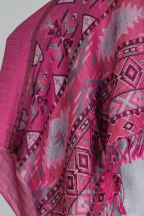 Close-up of a pink patterned fabric with tassels on a gray background