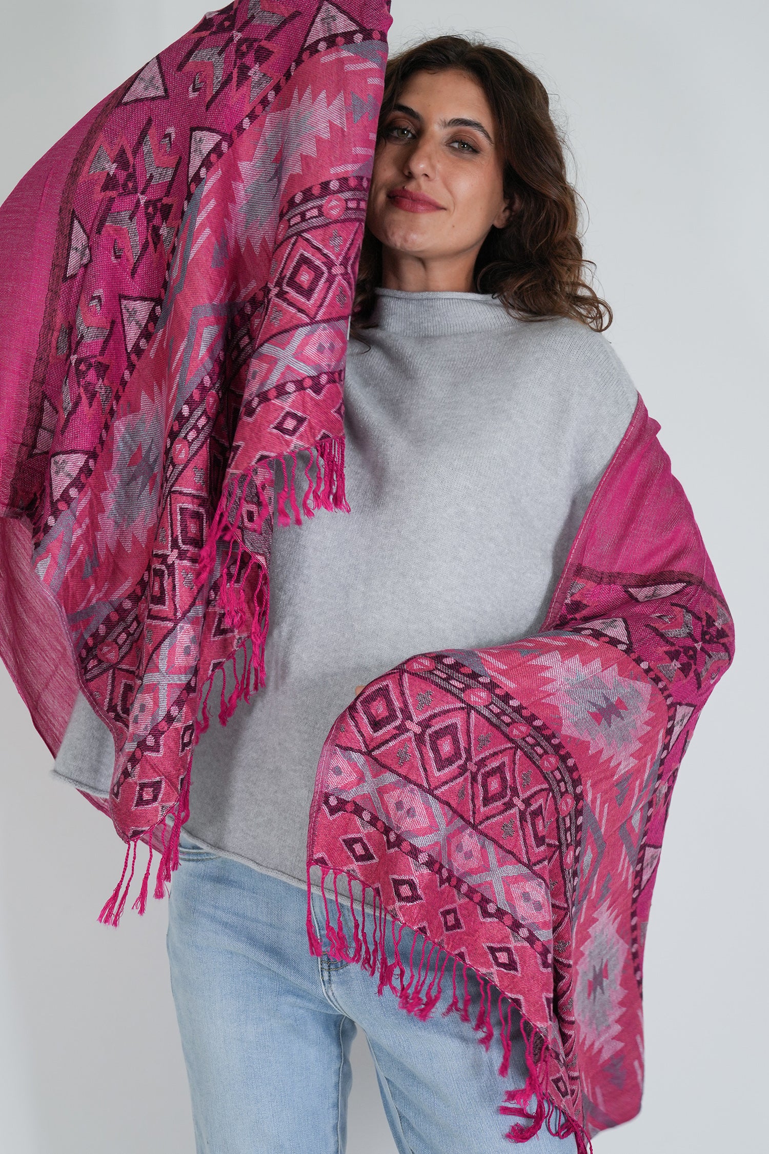 Woman wearing a pink patterned shawl over her shoulders against a white background