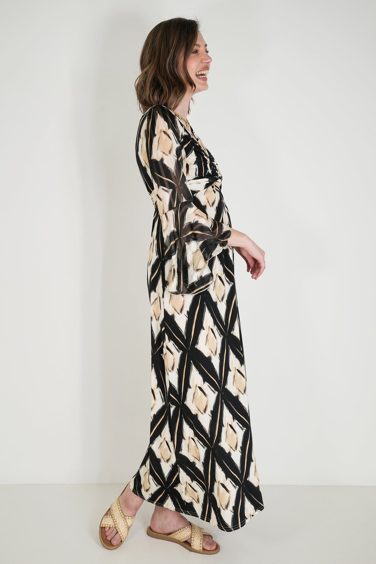 Woman wearing a long, patterned dress against a white background