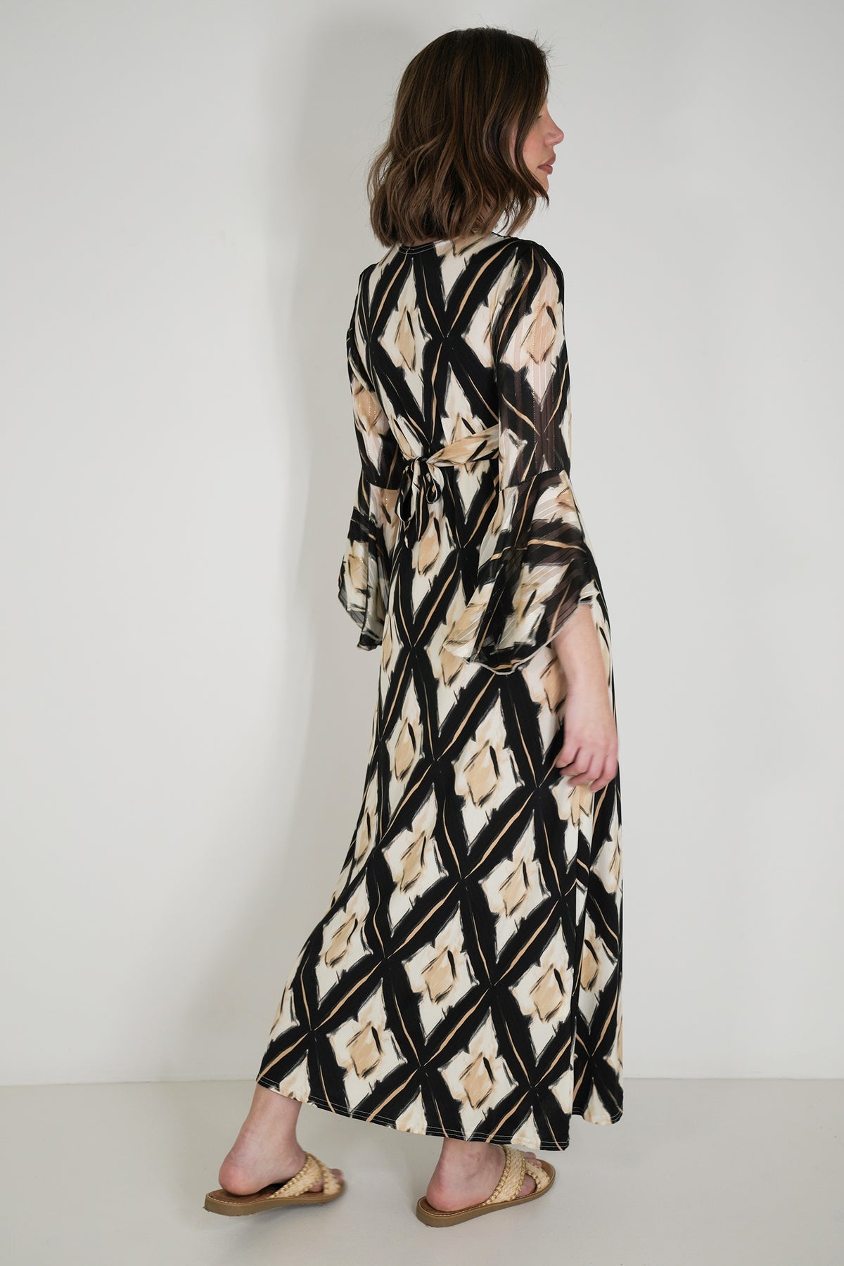 Woman wearing a long, patterned dress against a plain background