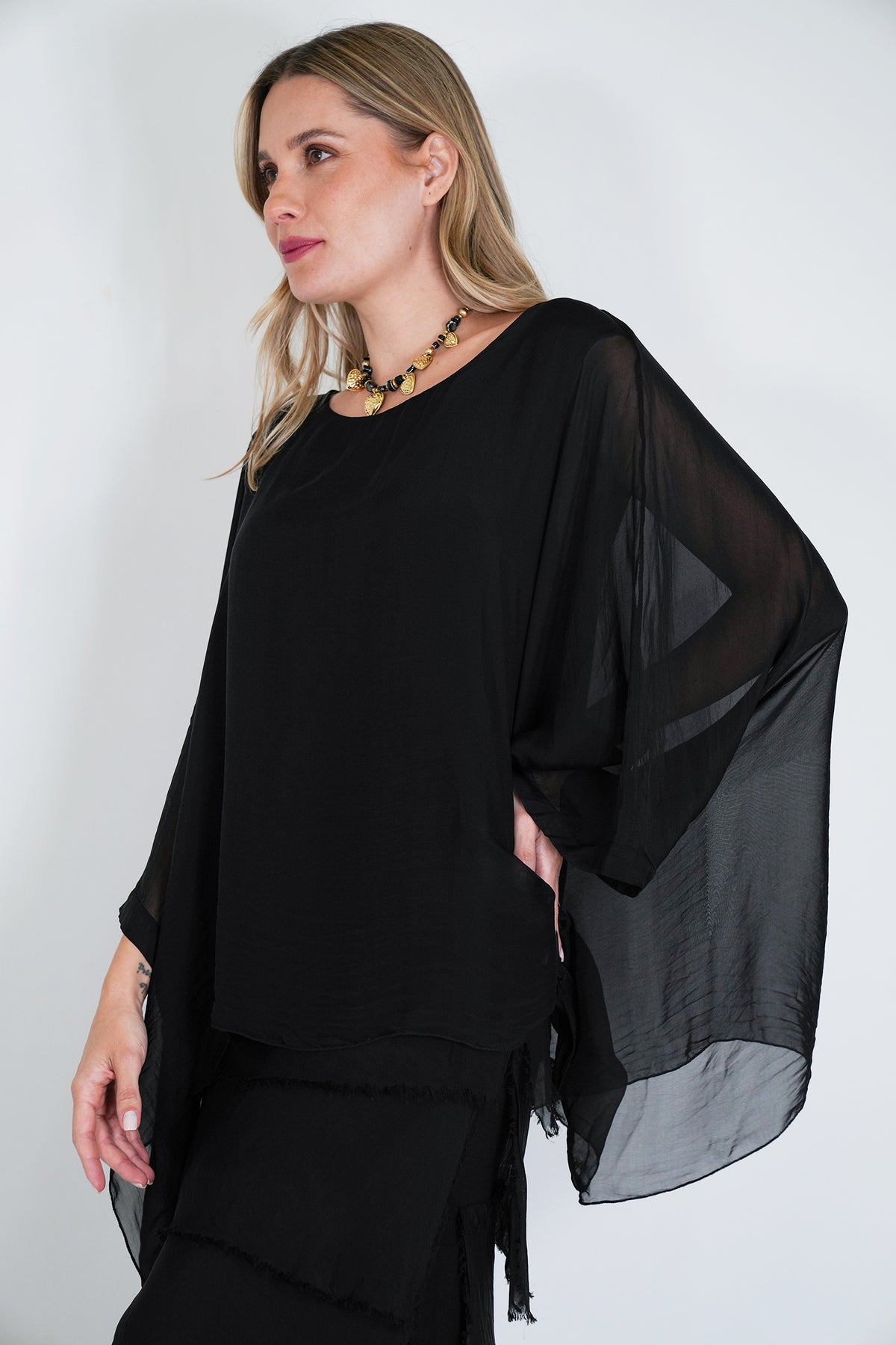 Woman wearing a black outfit with sheer sleeves against a white background