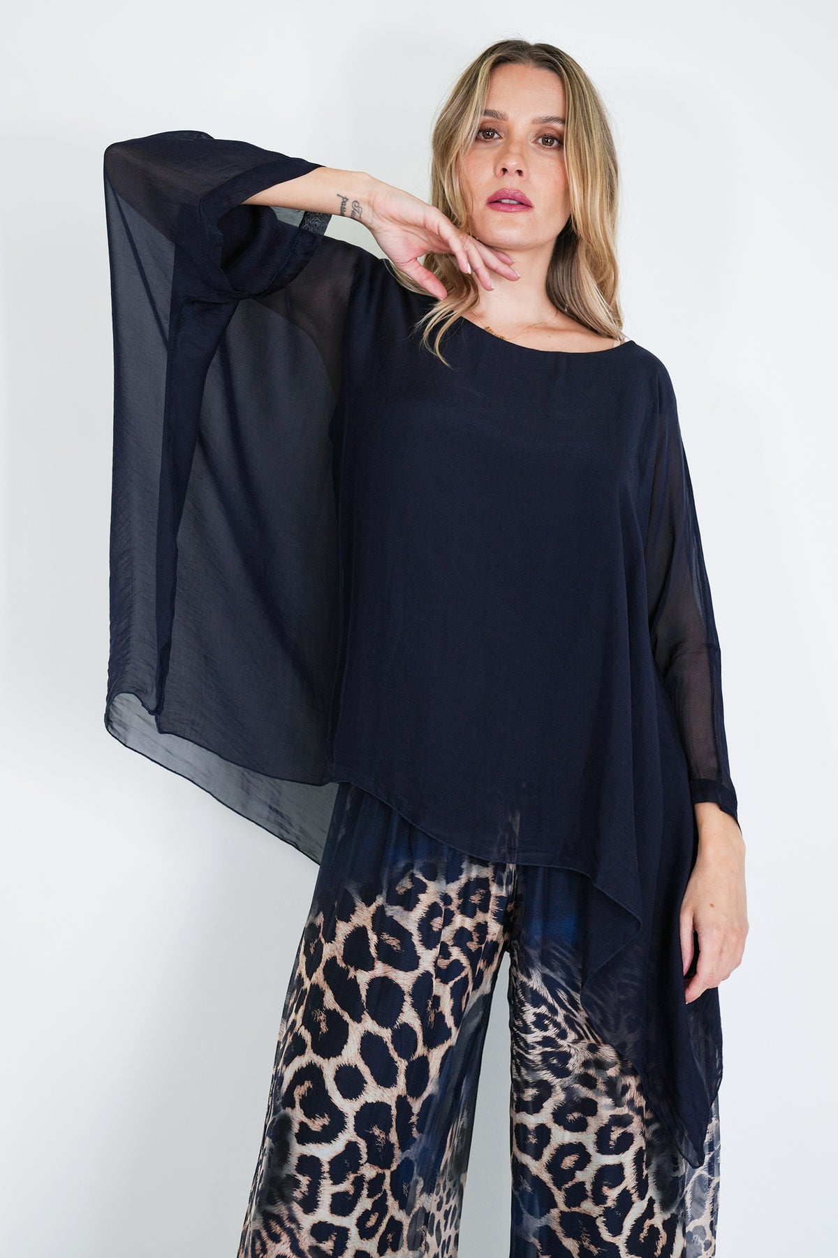 Woman wearing a black top and leopard print pants on a white background