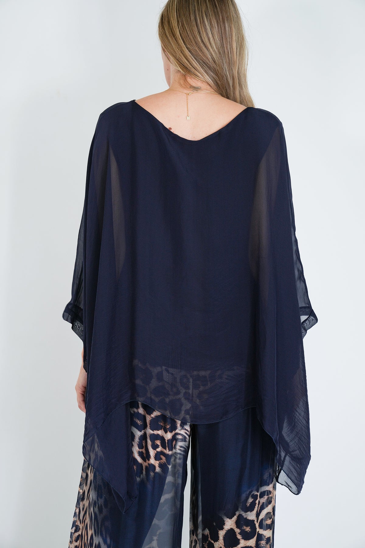 Navy blue sheer top worn by a person on a white background