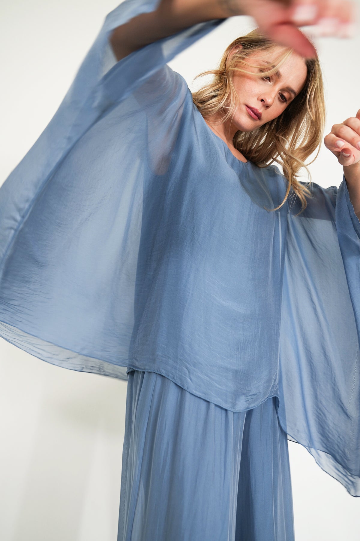 Woman wearing a flowing blue dress against a white background