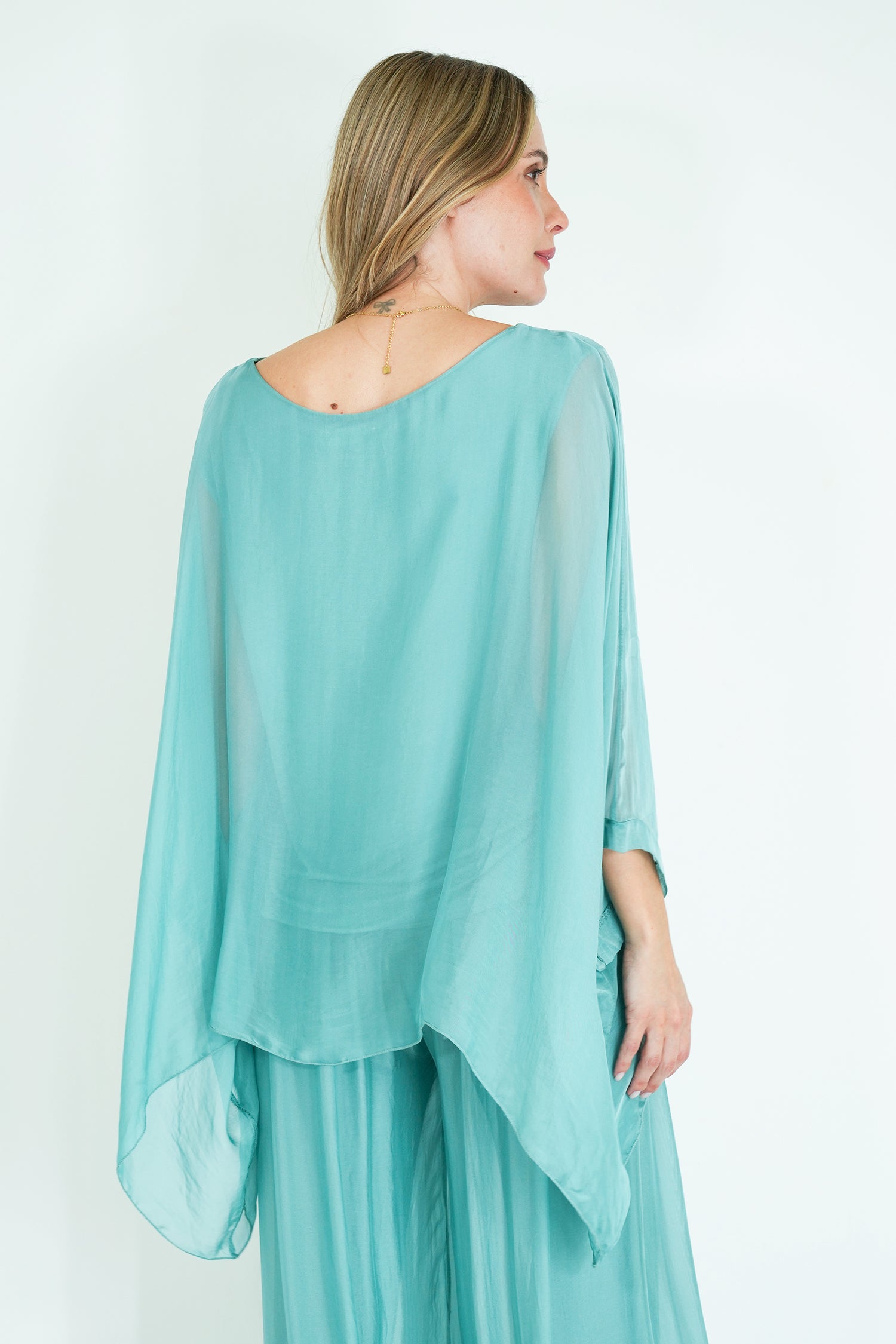 Woman wearing a light blue poncho over a matching outfit on a white background