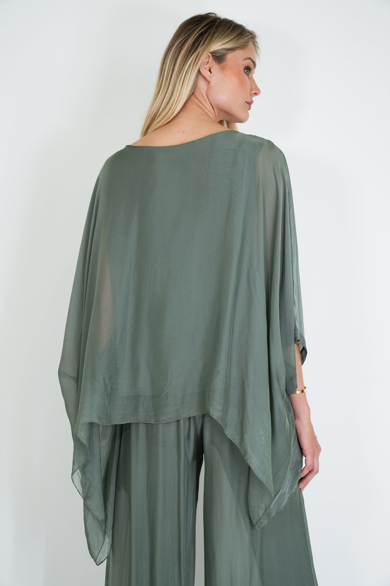 Woman wearing a green outfit with a sheer overlay against a white background