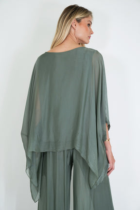 Woman wearing a green outfit with a sheer overlay against a white background