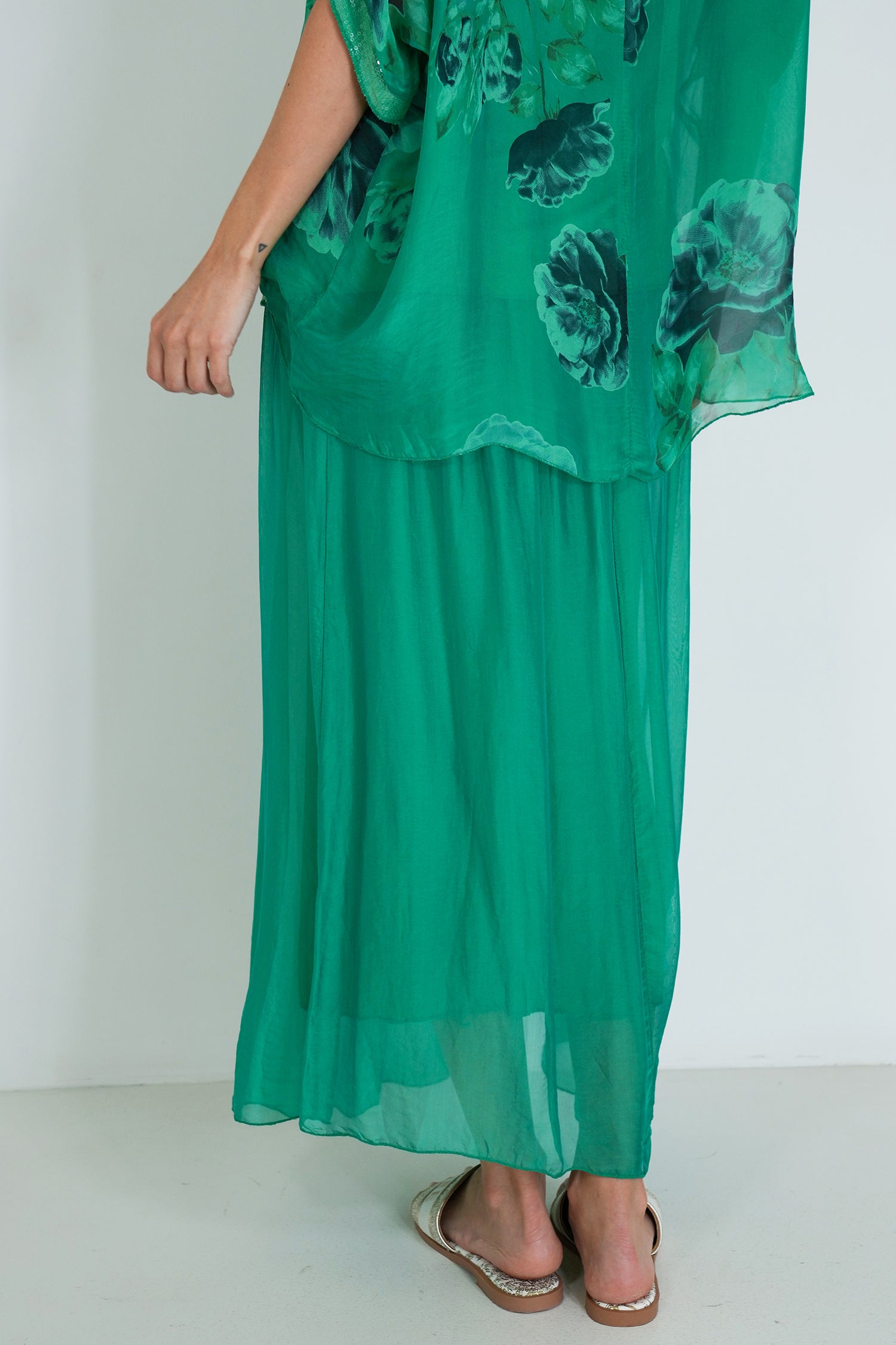 Green dress with floral pattern worn by a person on a white background