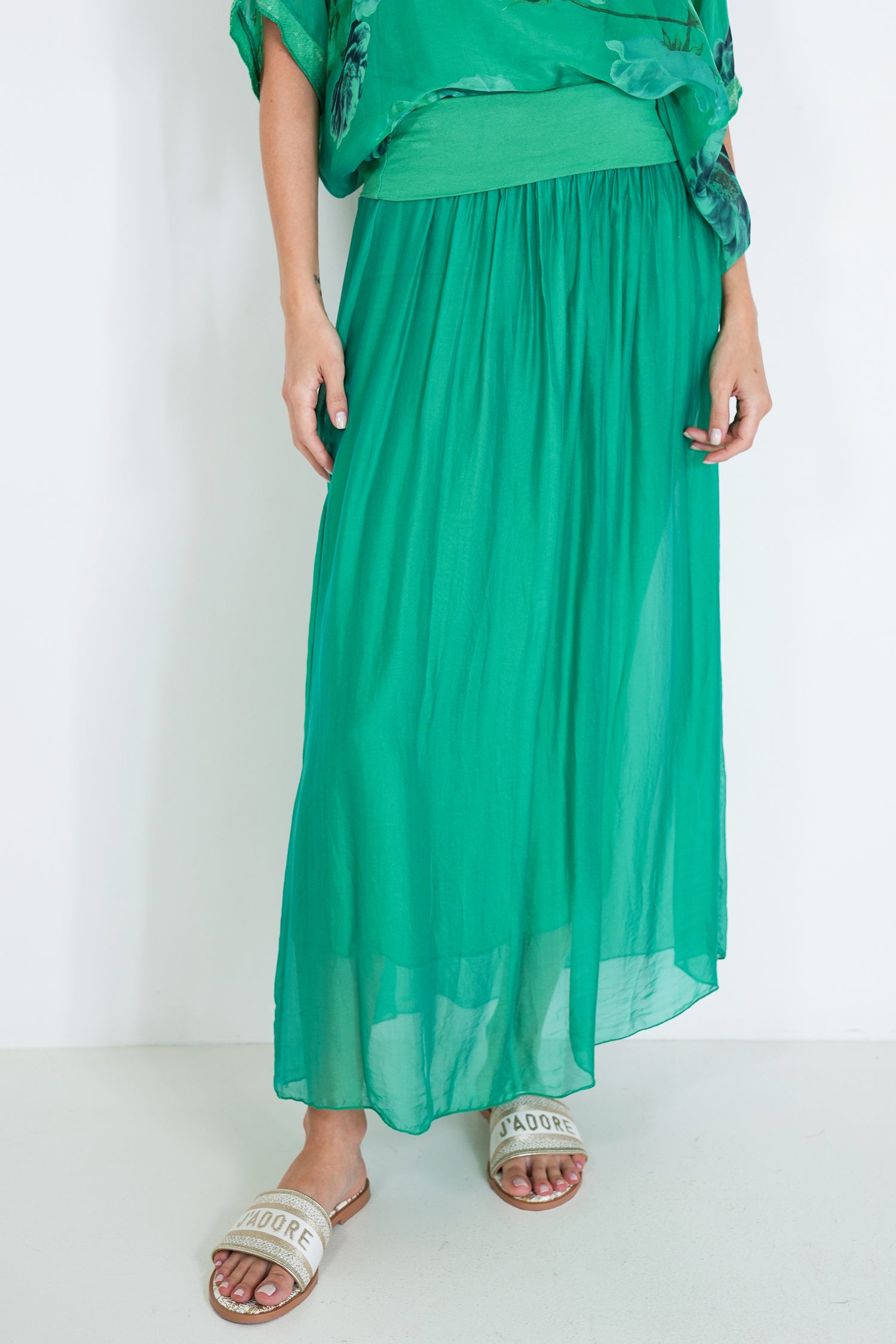 Person wearing a green outfit with a long skirt on a white background