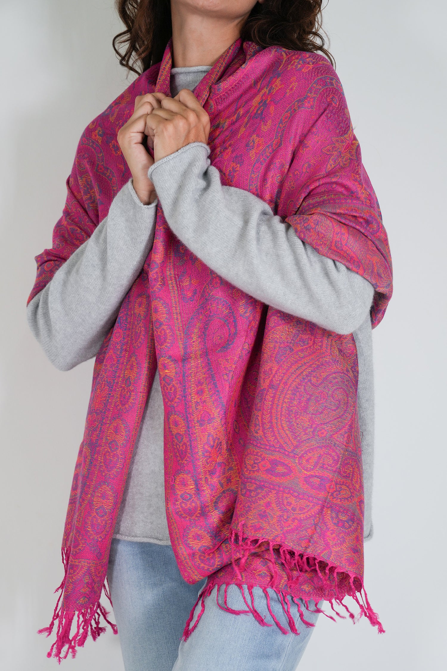 Person wearing a bright pink patterned scarf with a white background