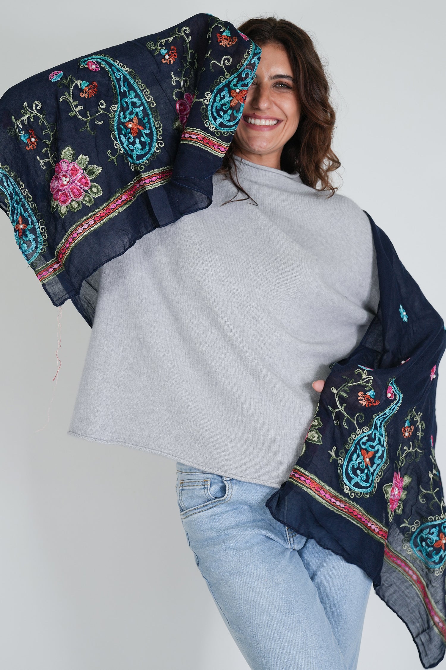 Woman holding a dark blue embroidered scarf against a white background