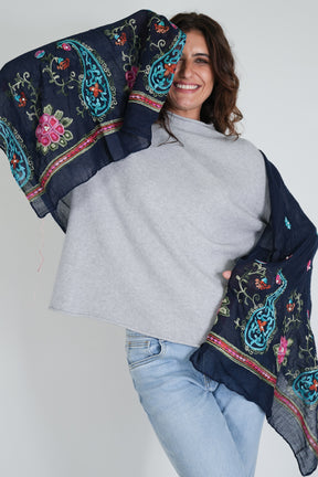 Woman holding a dark blue embroidered scarf against a white background
