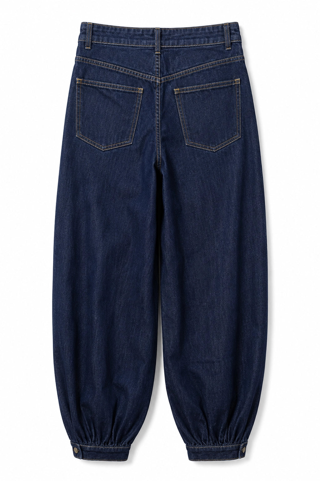 Back view of dark blue denim pants with a relaxed, baggy fit and elasticized cuffs, shown on a white background.