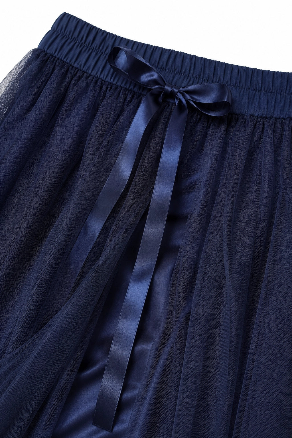 Close-up of a navy blue skirt with a sheer mesh texture, an elastic waistband, and a matching satin ribbon tied in a bow at the front.