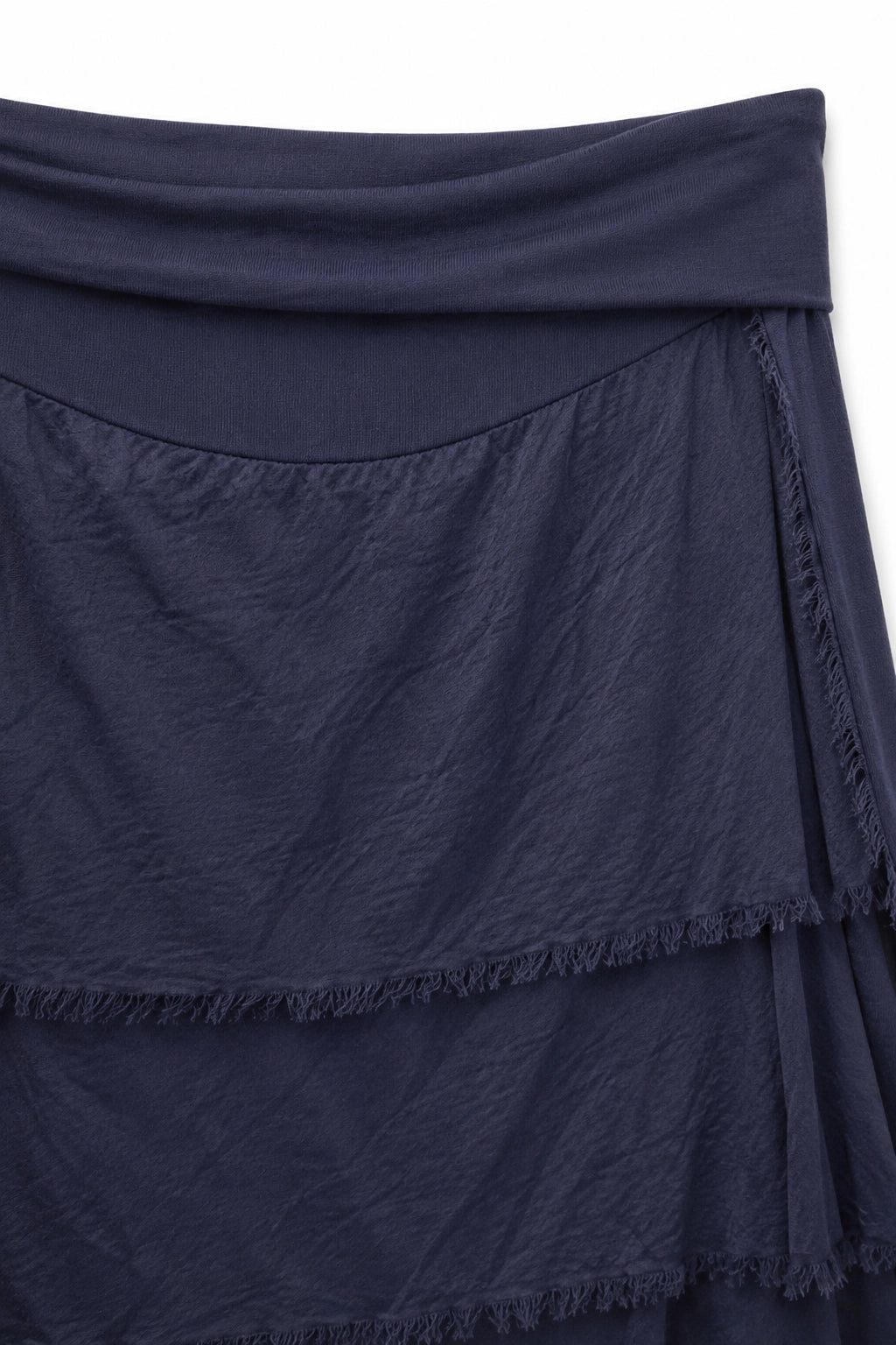 Close-up of a dark navy blue draped fabric garment with layered ruffles and fringed edges against a plain white background.