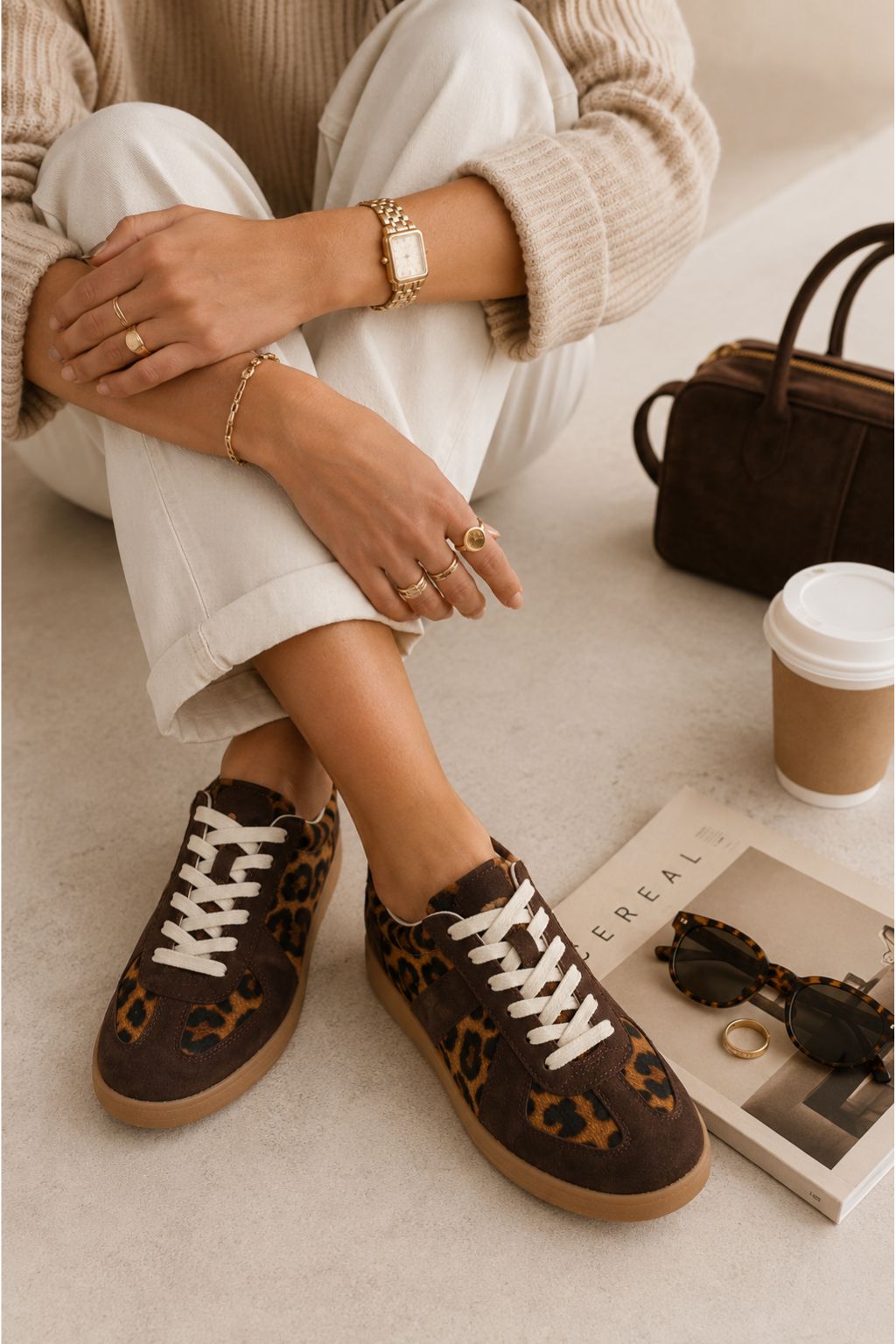Person wearing brown leopard print sneakers with a coffee cup and handbag in the background.