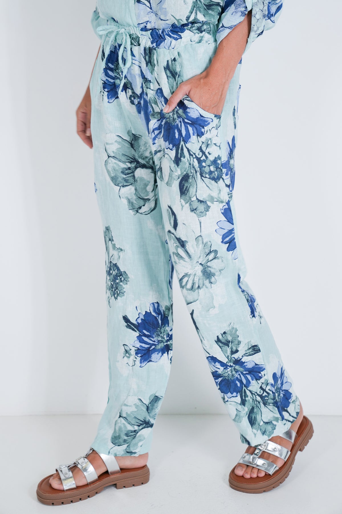Person wearing blue floral pants with a white background