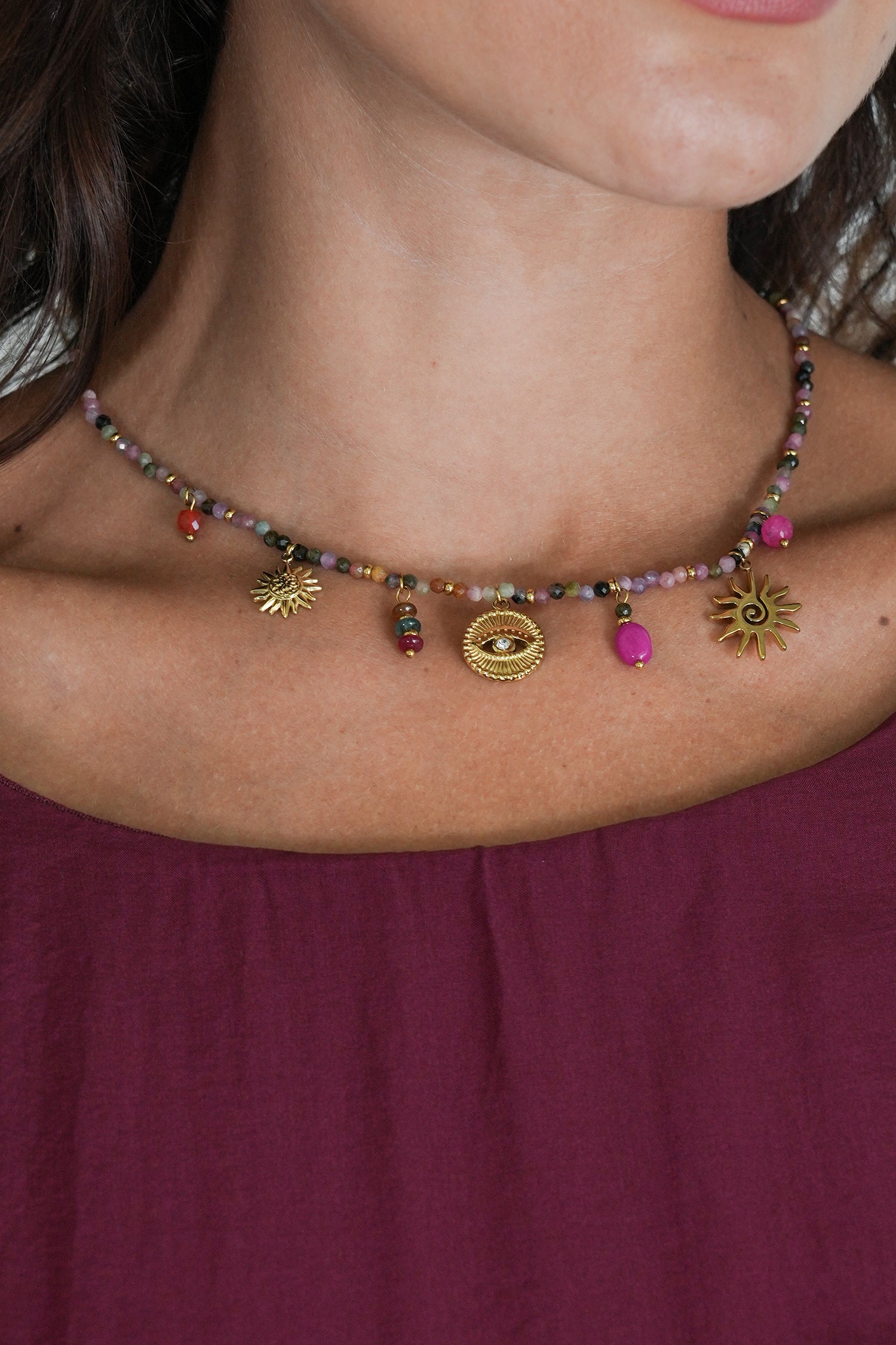 Close-up of a person wearing a beaded necklace with colorful beads and gold accents.