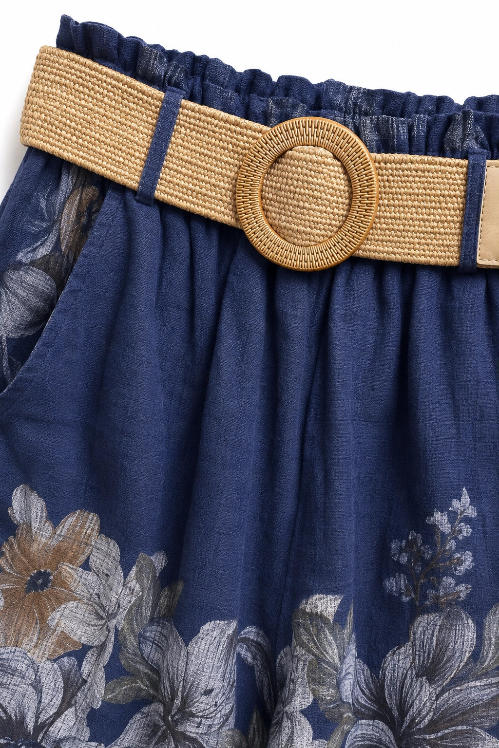 Close-up of a navy blue floral skirt with a wide woven tan belt featuring a round woven buckle.