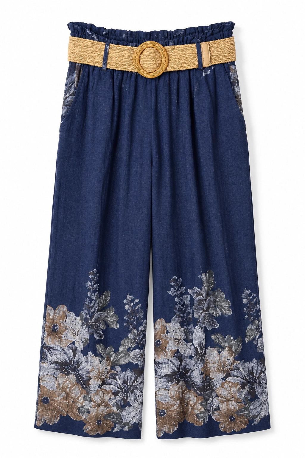 A pair of navy blue wide-leg cropped pants featuring a floral print in beige, white, and gray at the hem, styled with a tan woven belt and round tan buckle.