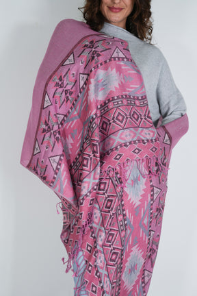 Person wearing a pink patterned shawl over a gray sweater on a white background