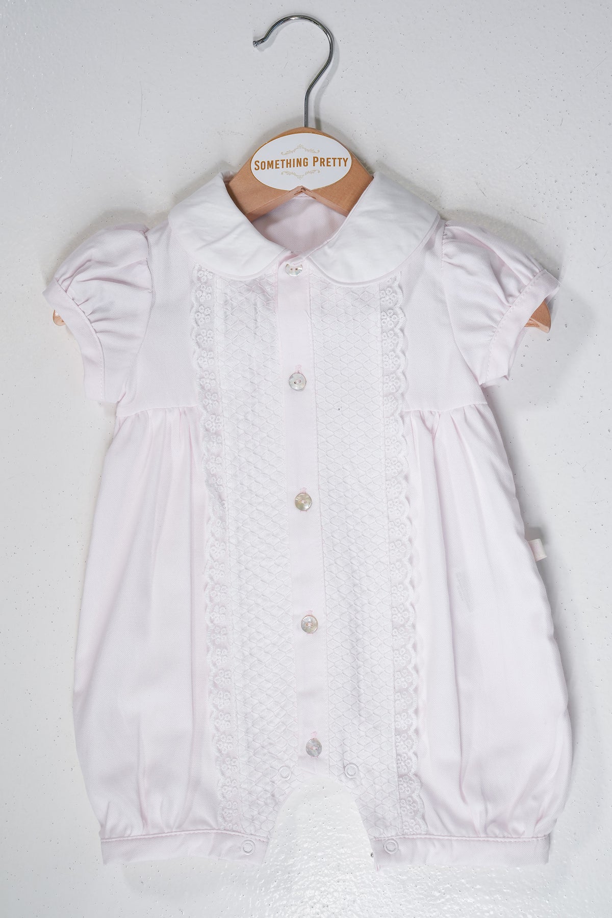 Pink Romper on a hanger with 'Something Pretty' label against a white background