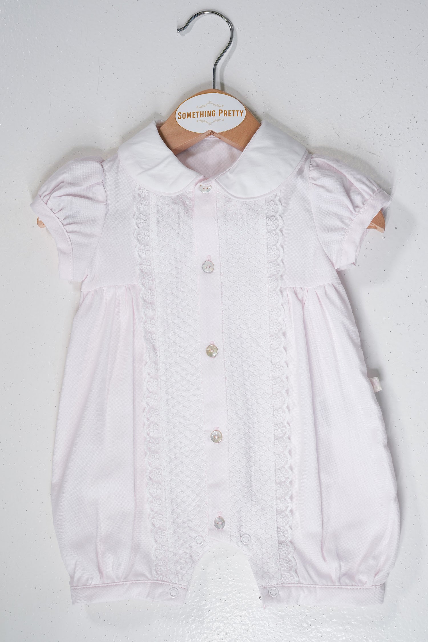 Pink Romper on a hanger with 'Something Pretty' label against a white background