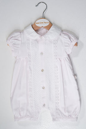 Pink Romper on a hanger with 'Something Pretty' label against a white background