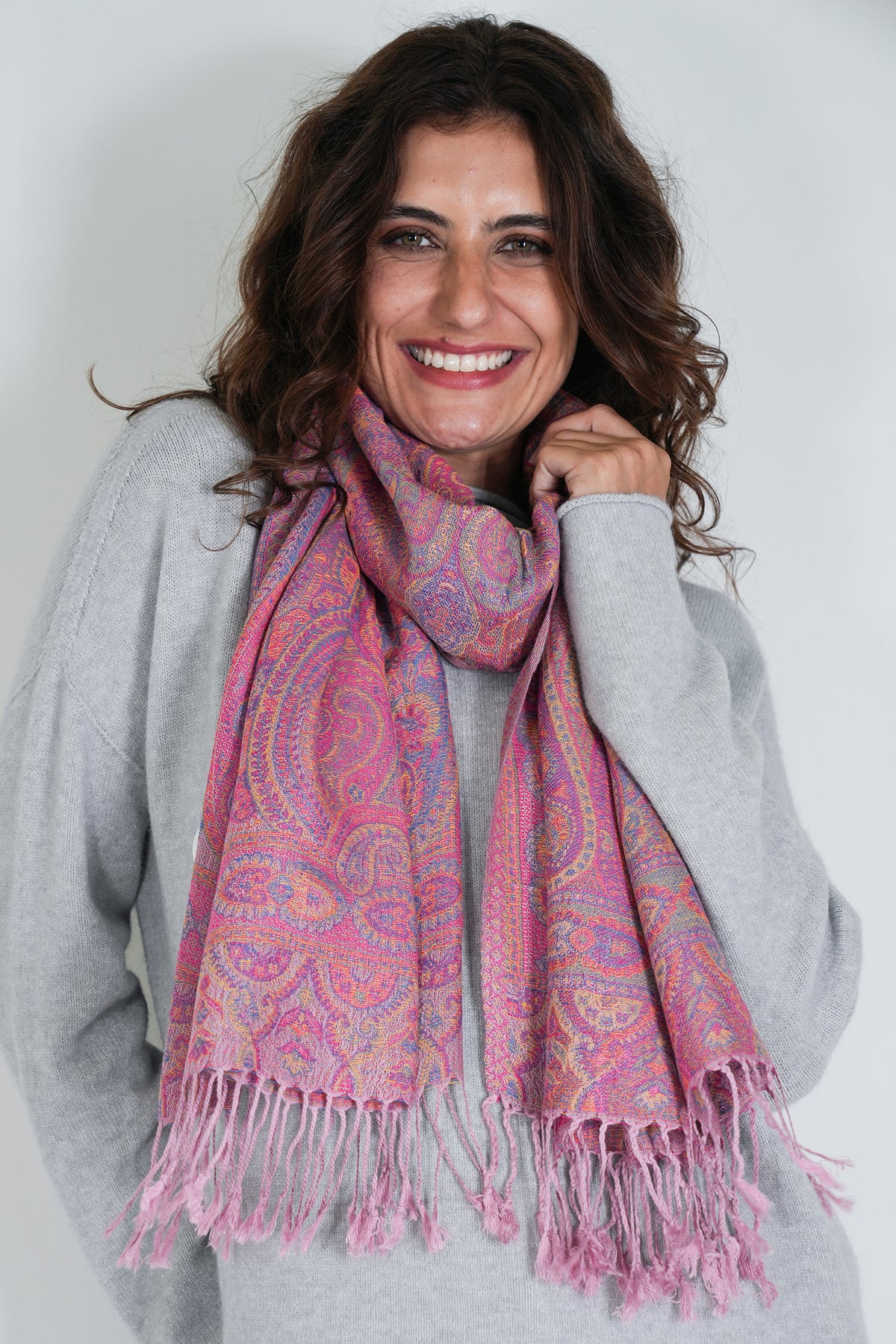 Woman wearing a pink patterned scarf against a white background