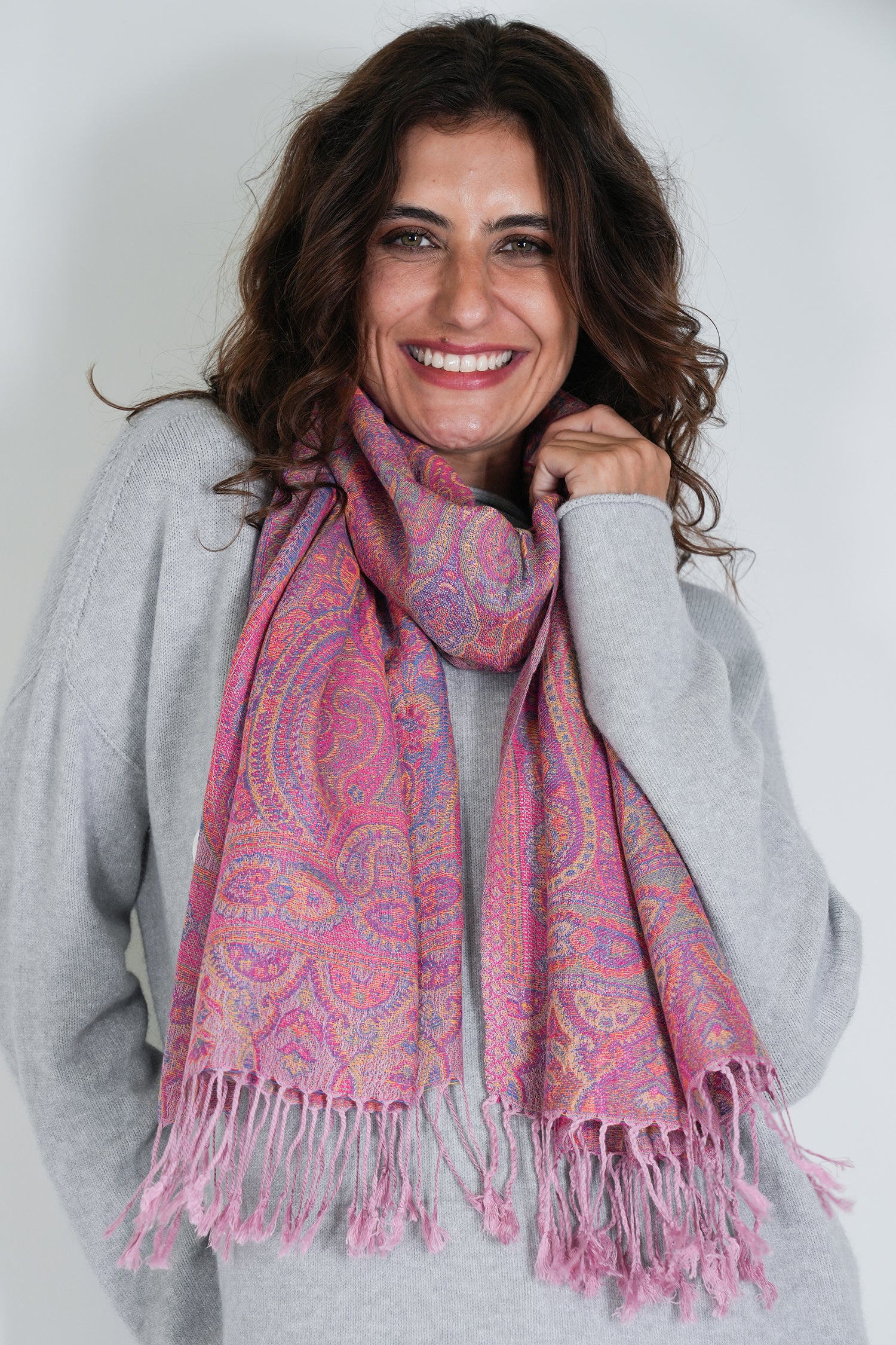 Woman wearing a pink patterned scarf against a white background