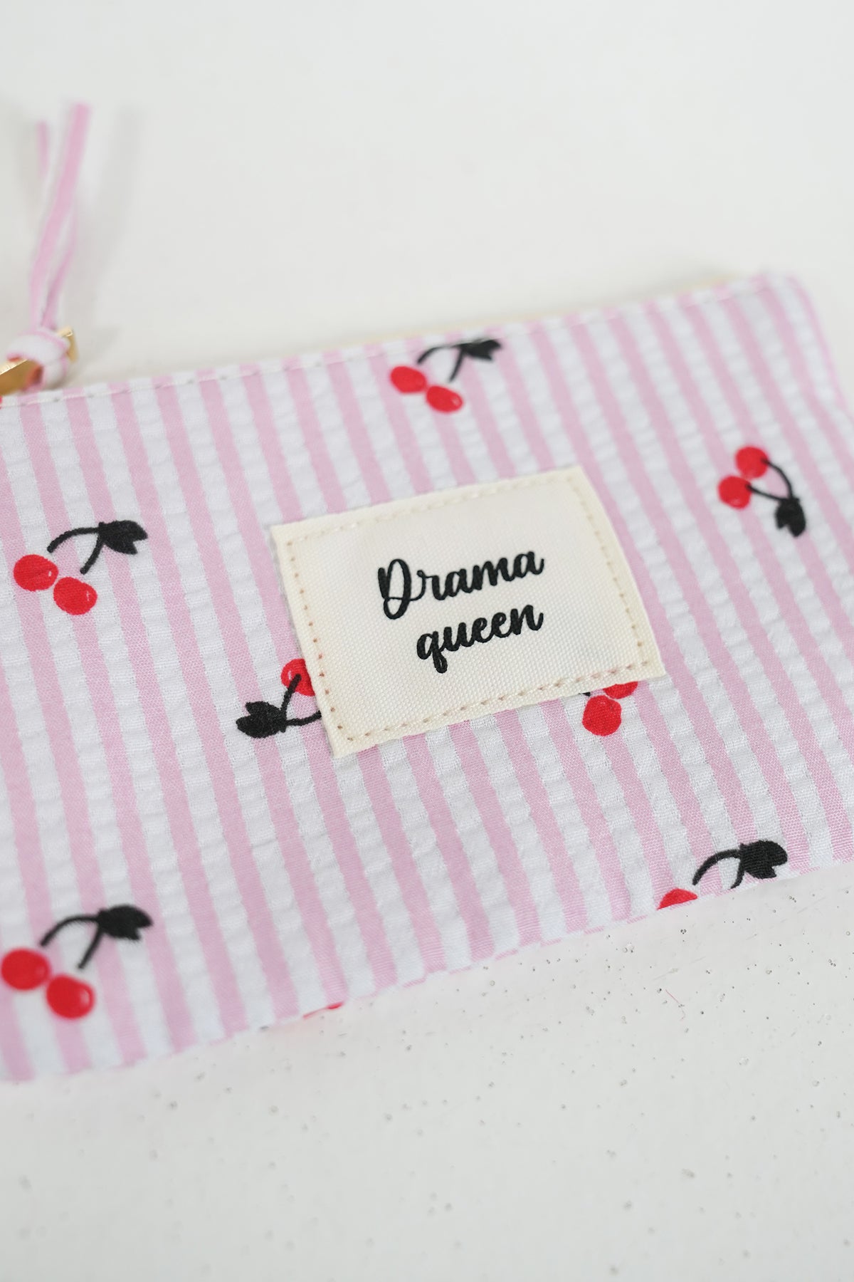 Fabric with pink stripes and cherry pattern, featuring a label with 'Drama queen' text.