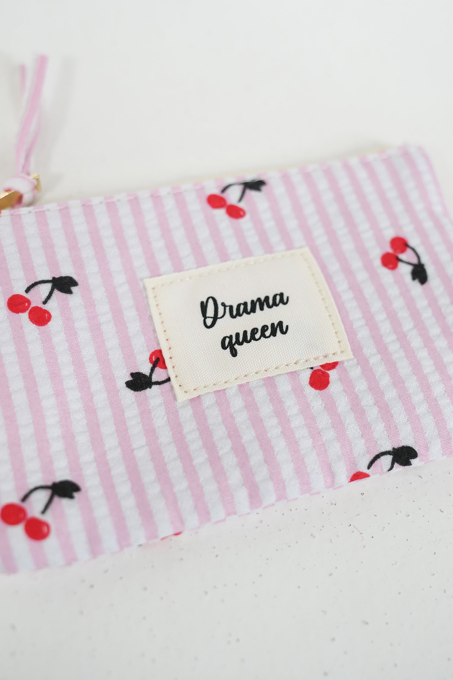 Fabric with pink stripes and cherry pattern, featuring a label with 'Drama queen' text.
