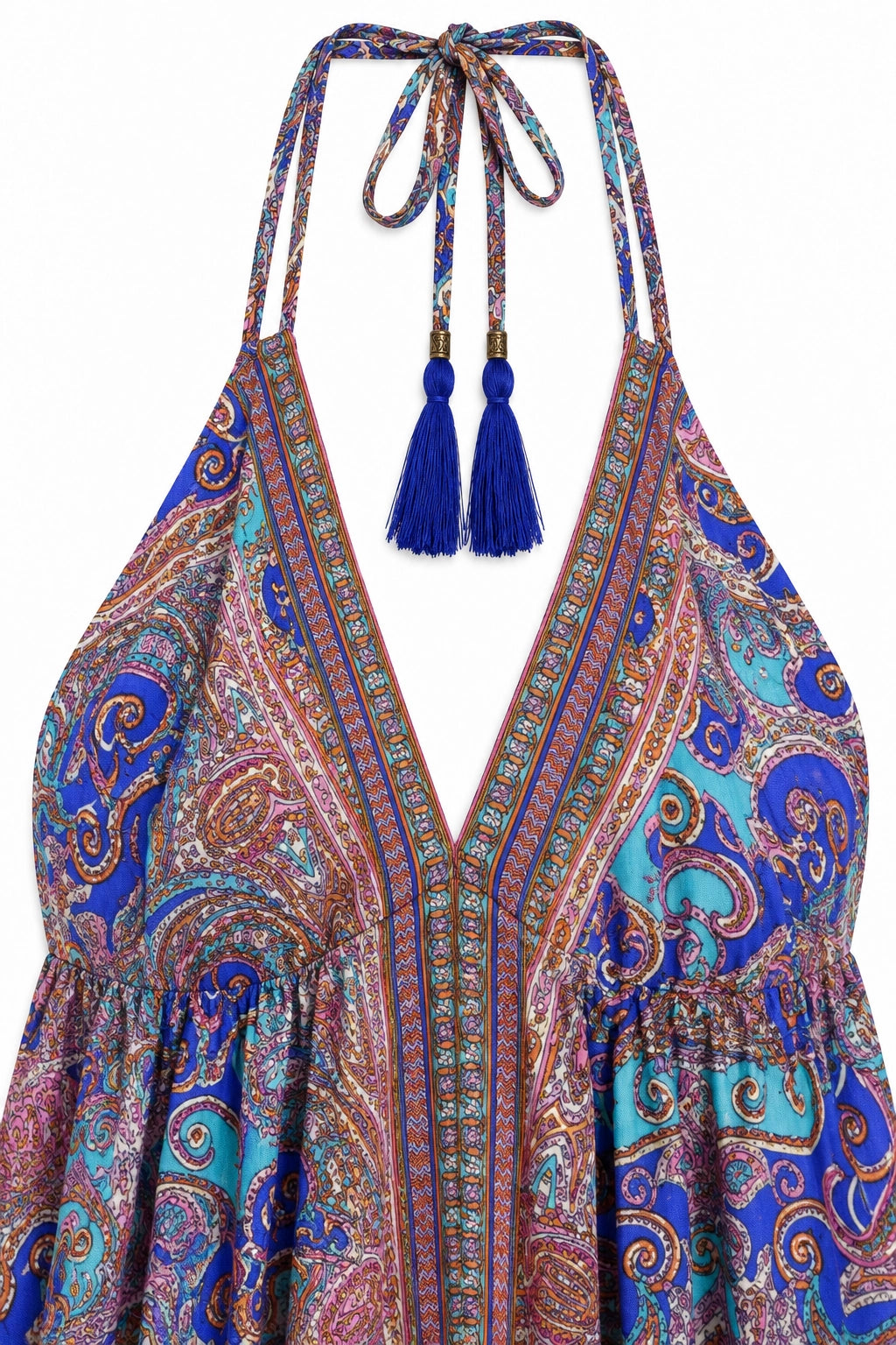 A close-up of a halter-neck dress featuring a vibrant paisley pattern in shades of blue, purple, pink, and orange. The dress has a deep V-neckline with a tie at the top and long blue tassels hanging from the gold-tone rings.