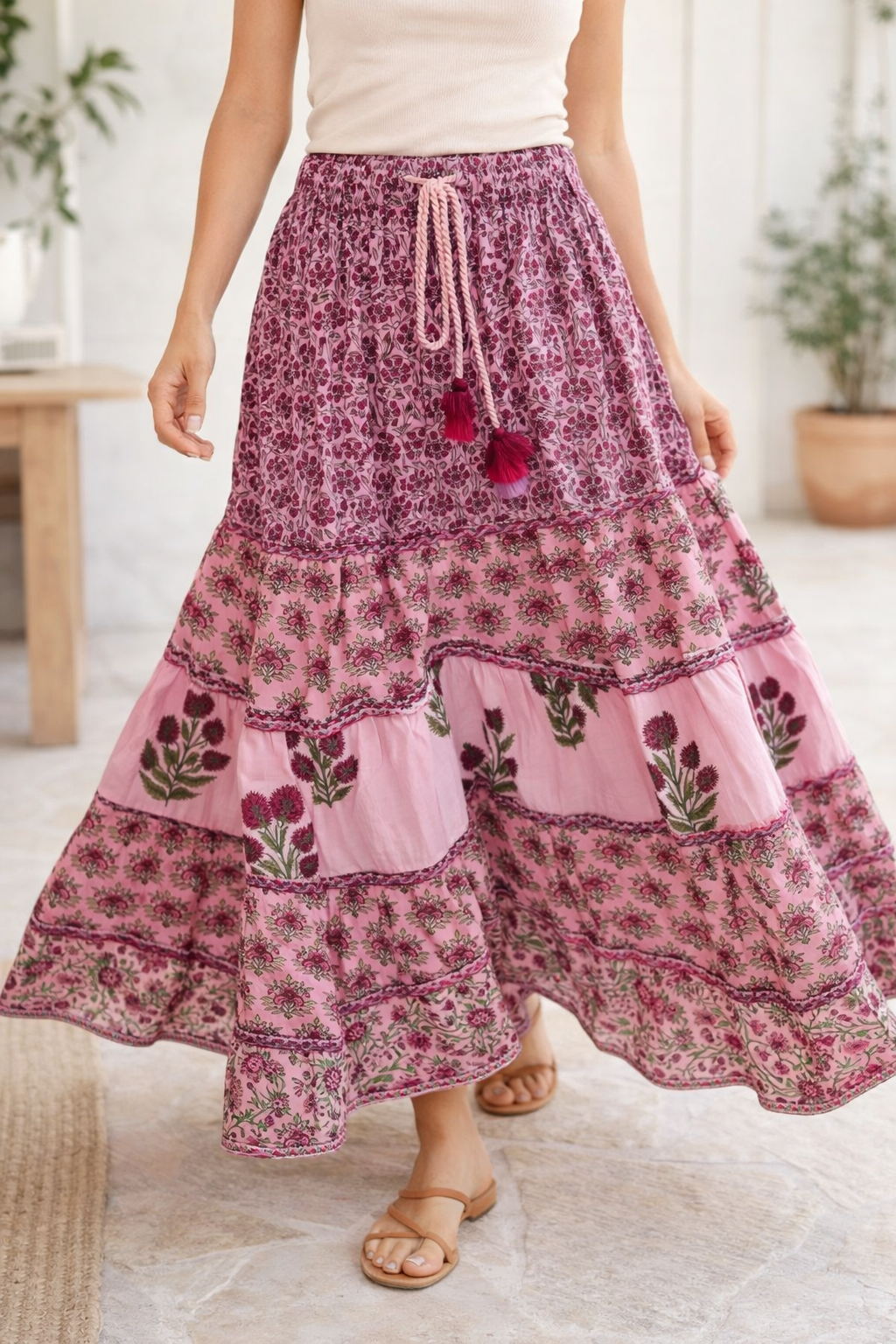 Person wearing a pink floral tiered skirt with a white top indoors.