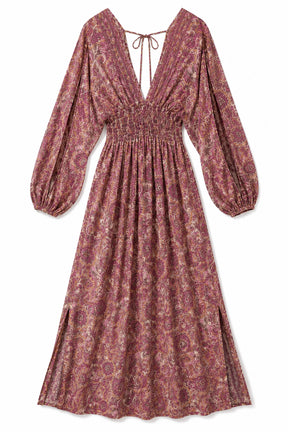 A long-sleeve midi dress with a smocked waist and a deep V-neckline tied at the collar, featuring an all-over paisley pattern in dusty rose, mauve, and burgundy tones, shown against a plain white background.